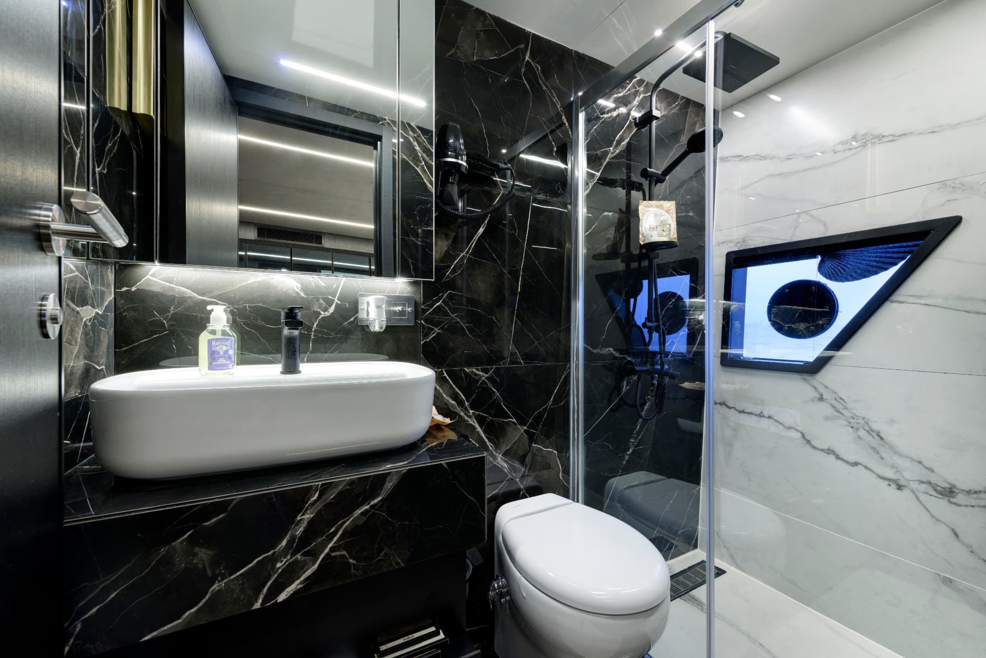 Siyah-beyaz mermer lüks banyo: serbest beyaz lavabo, siyah armatürler, cam duş ve duvara monte heykelsi ekran